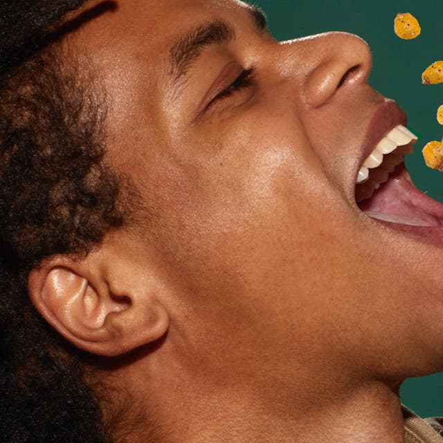 man pouring corn nuts into his mouth